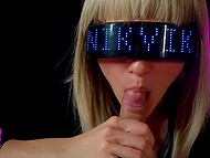 Seksīga blondīne kiberpanka tērpā uzmanīgi sūc dzimumlocekli, līdz saņem visu mēli
