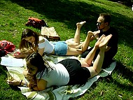 Two girls remove their shoes and offer their bare feet to a stranger man, who worships their soles in the park 4